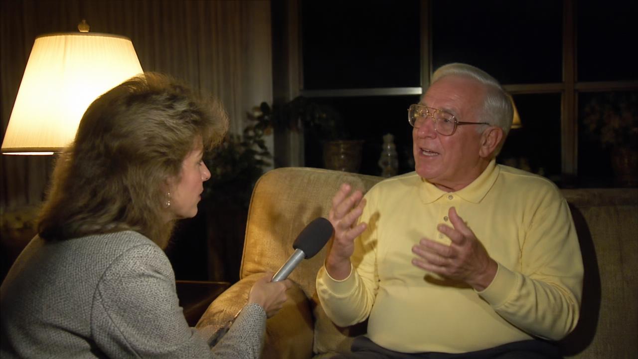 A news reporter interviewing an elderly man on his sofa the week the story went viral